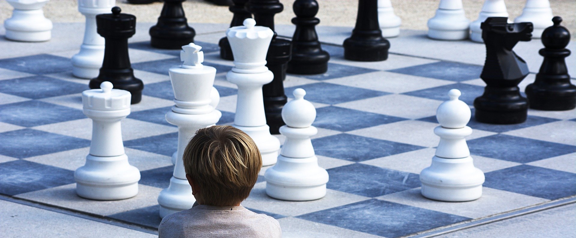 A boy looking at the chess pieces
